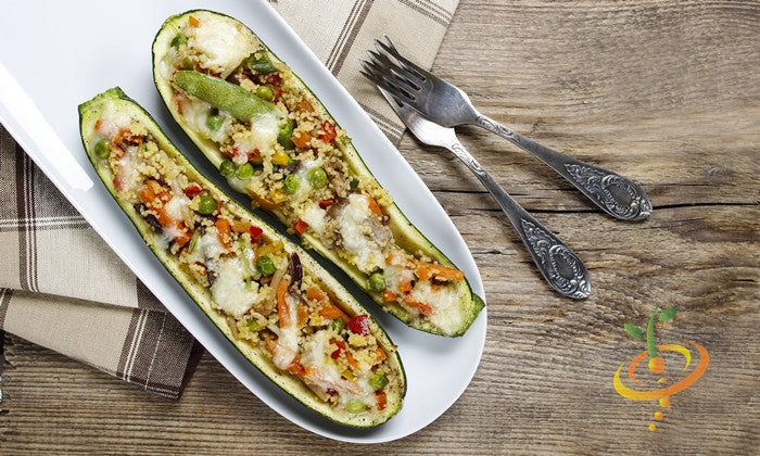 Stuffed Black Beauty zucchini boats with vegetables and melted cheese on white plate