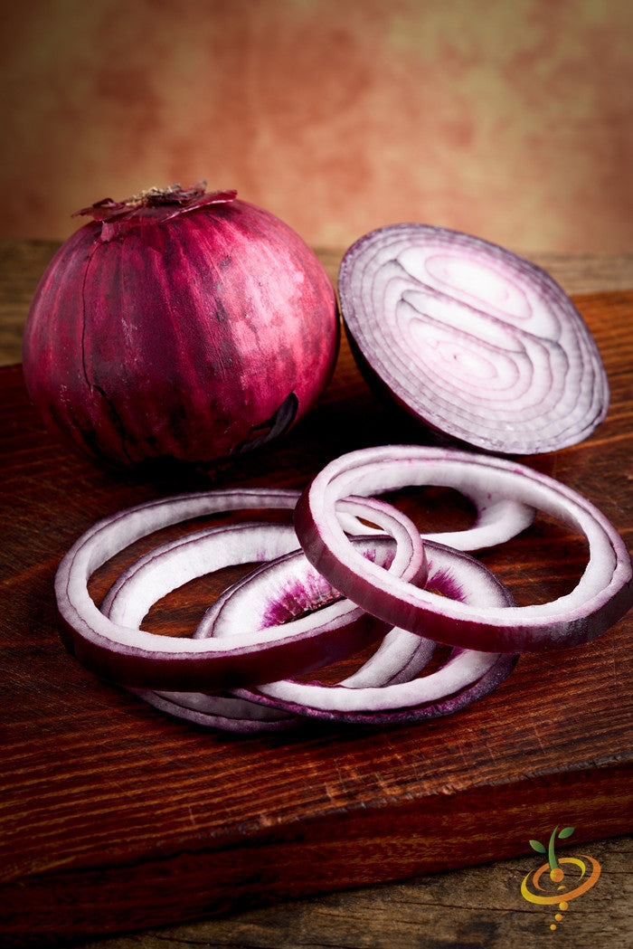 Red Burgundy onion whole and sliced on wooden surface with warm background