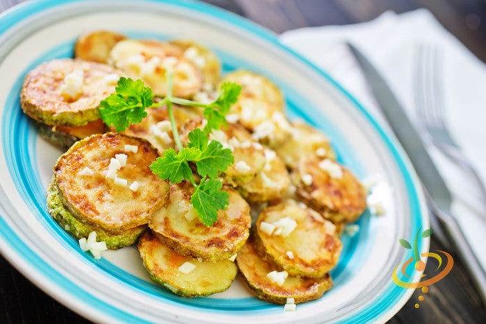 Fried zucchini slices garnished with herbs and garlic on a blue-rimmed plate